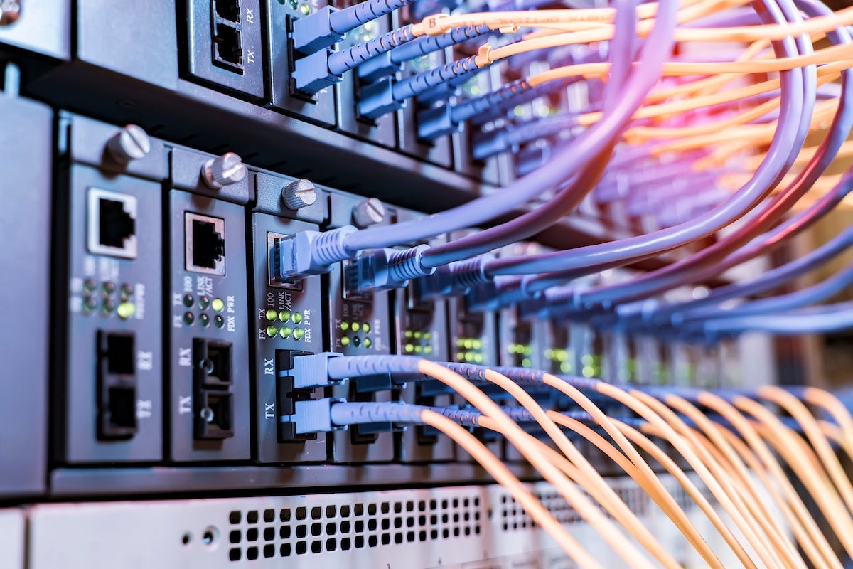 server rack with fiber optic cables attached to front panel switch ports