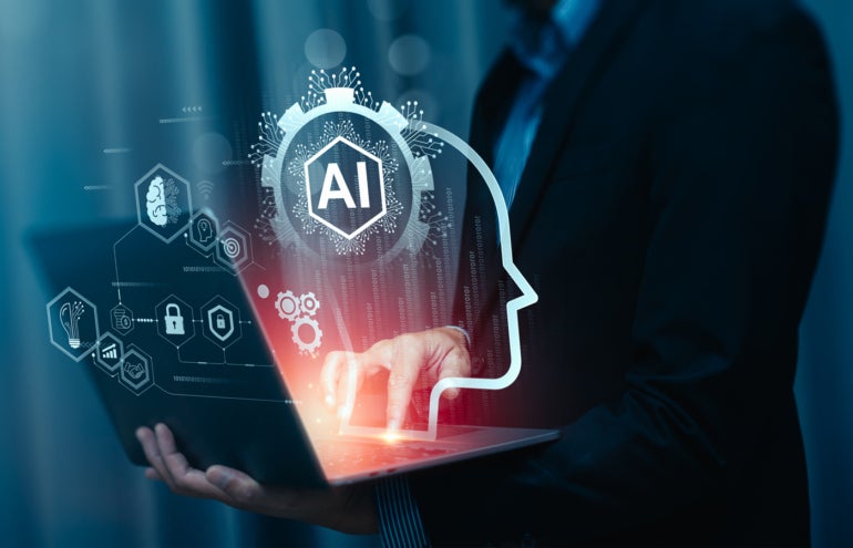 IT professional using a laptop with virtual AI-related images coming out on the display.